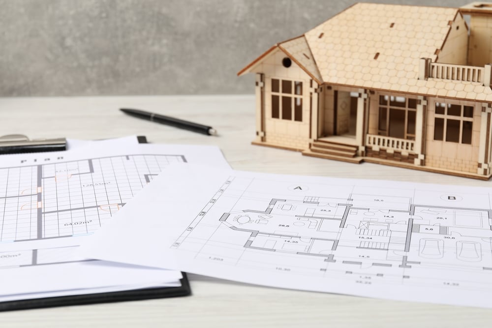 Real,Estate.,House,Model,And,Floor,Plan,On,White,Wooden ouse model and floor plan on white wooden table, closeup