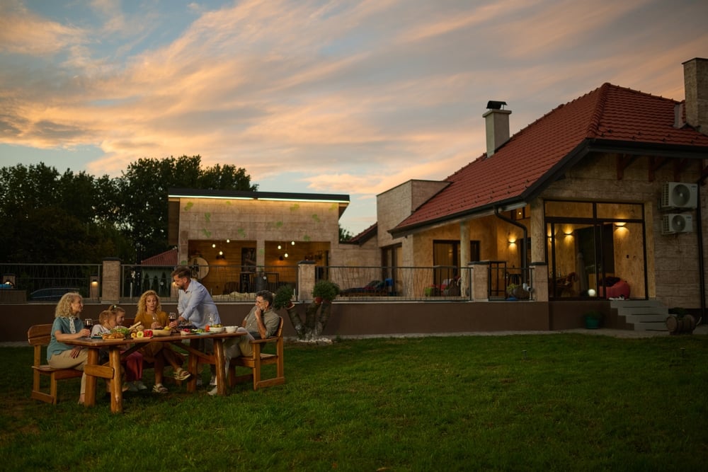 Family,Is,Sitting,At,A,Wooden,Table,In,Their,Backyard,